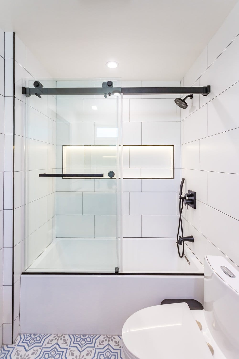 The bath from the end, black fixtures above the niche.