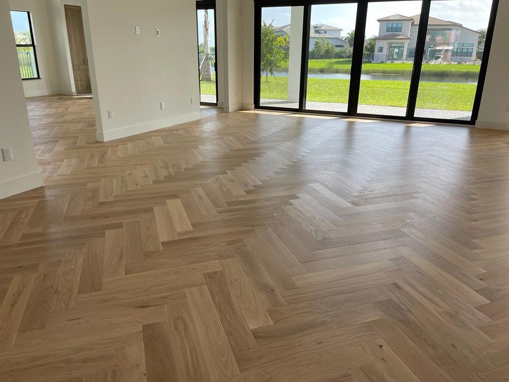 Herringbone flooring in an open room with full-height windows