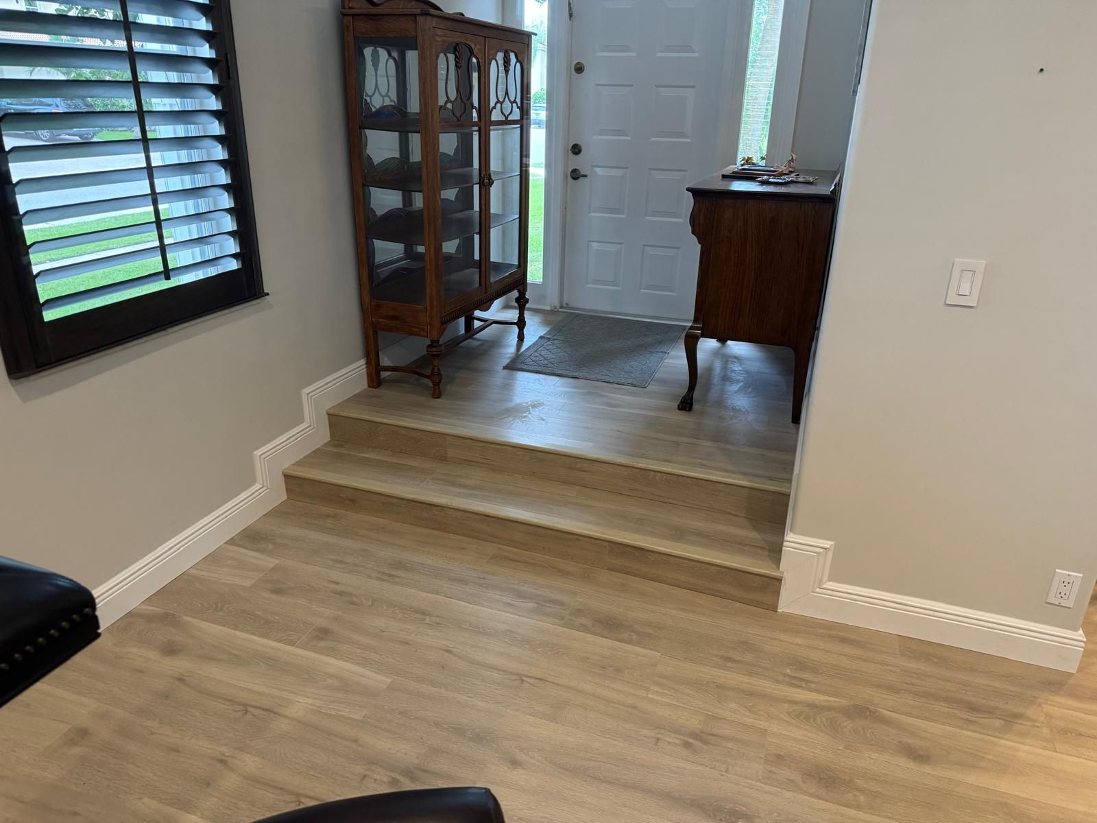 Plank flooring in a hallway with a panelled door open