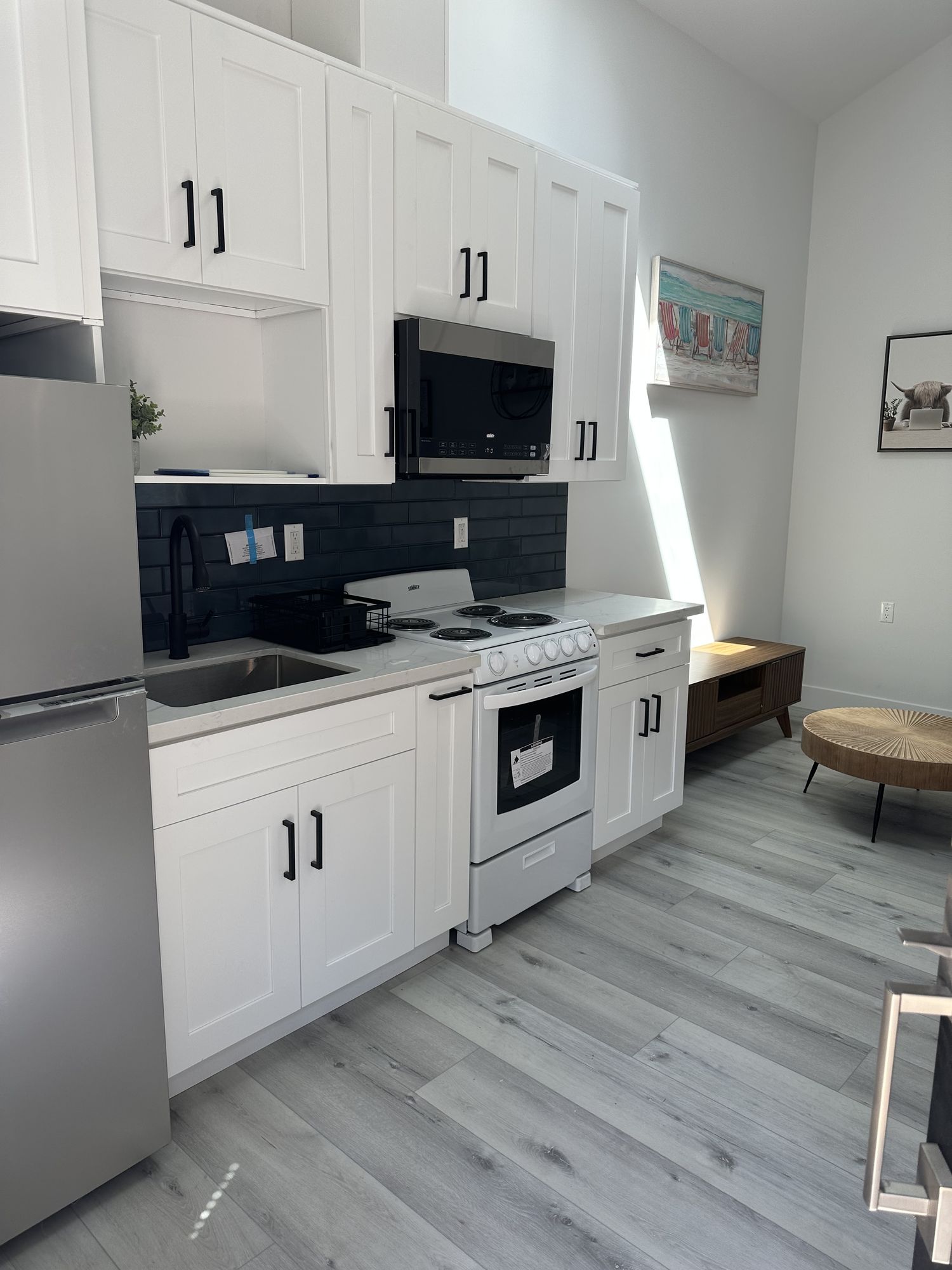 Compact full kitchen in an accessory dwelling unit with white shaker fronts and a dark subway backsplash