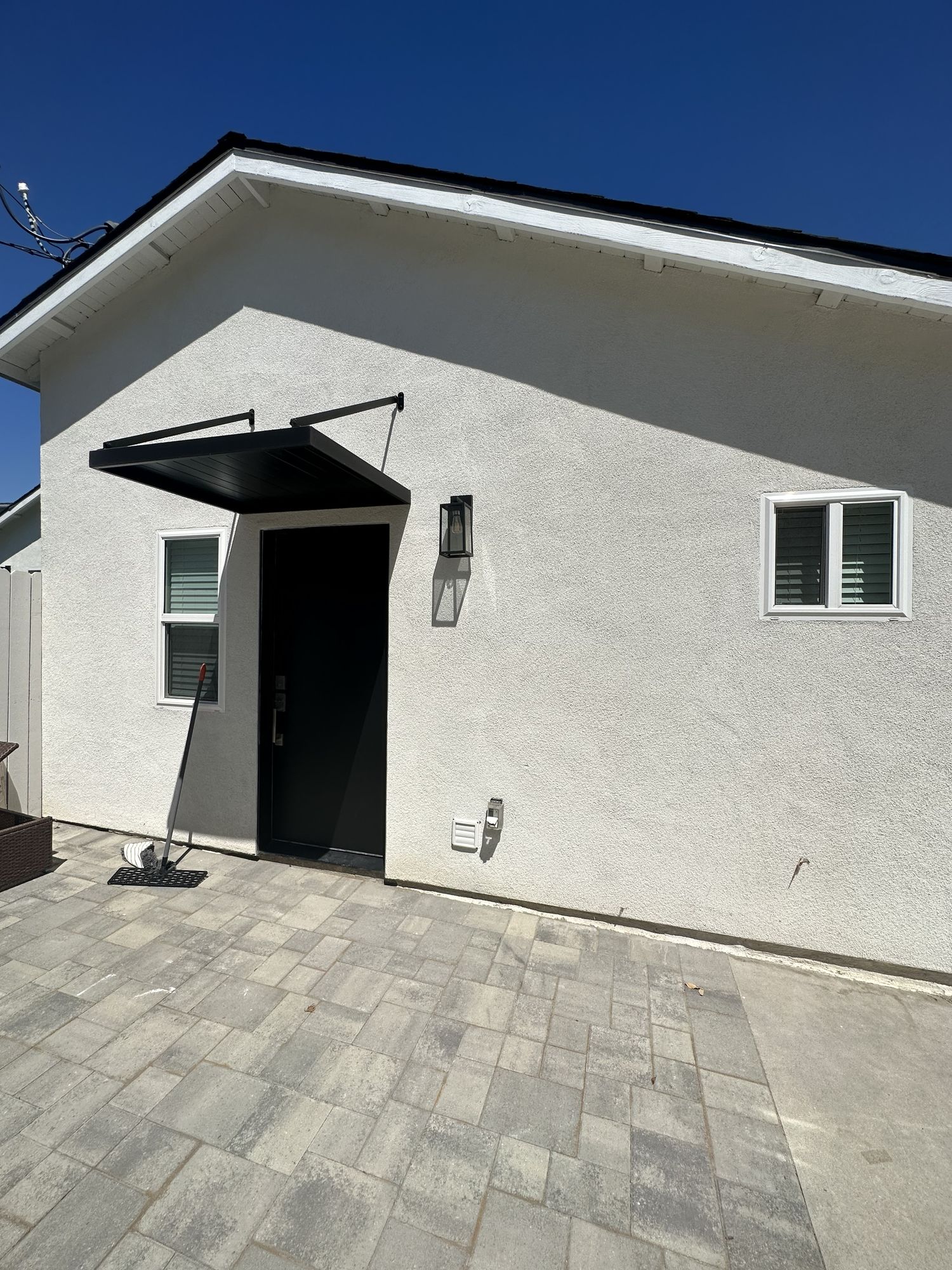 Completed single-level accessory dwelling unit seen from its own paved entrance with a black door canopy