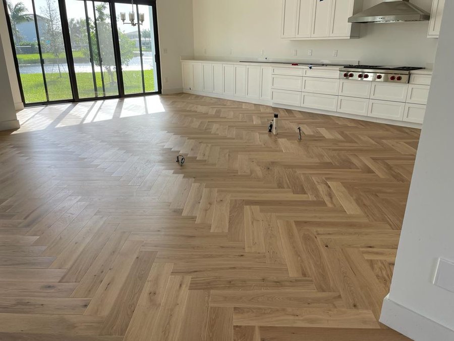 Herringbone timber flooring laid across a large open space beside a glazed wall