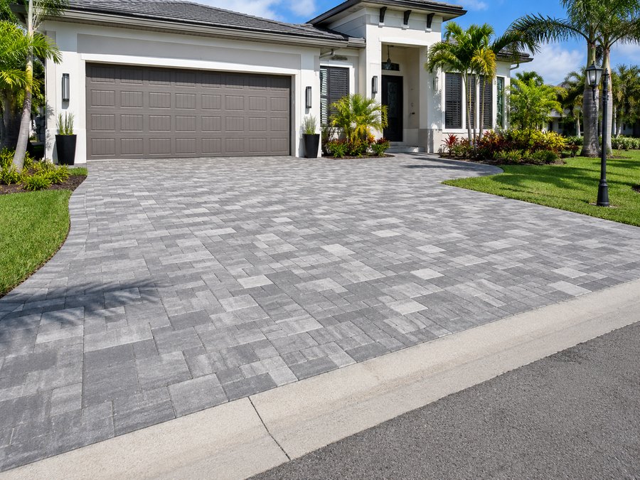 Large-format grey paver driveway with a contrasting soldier-course border at a modern South Florida home
