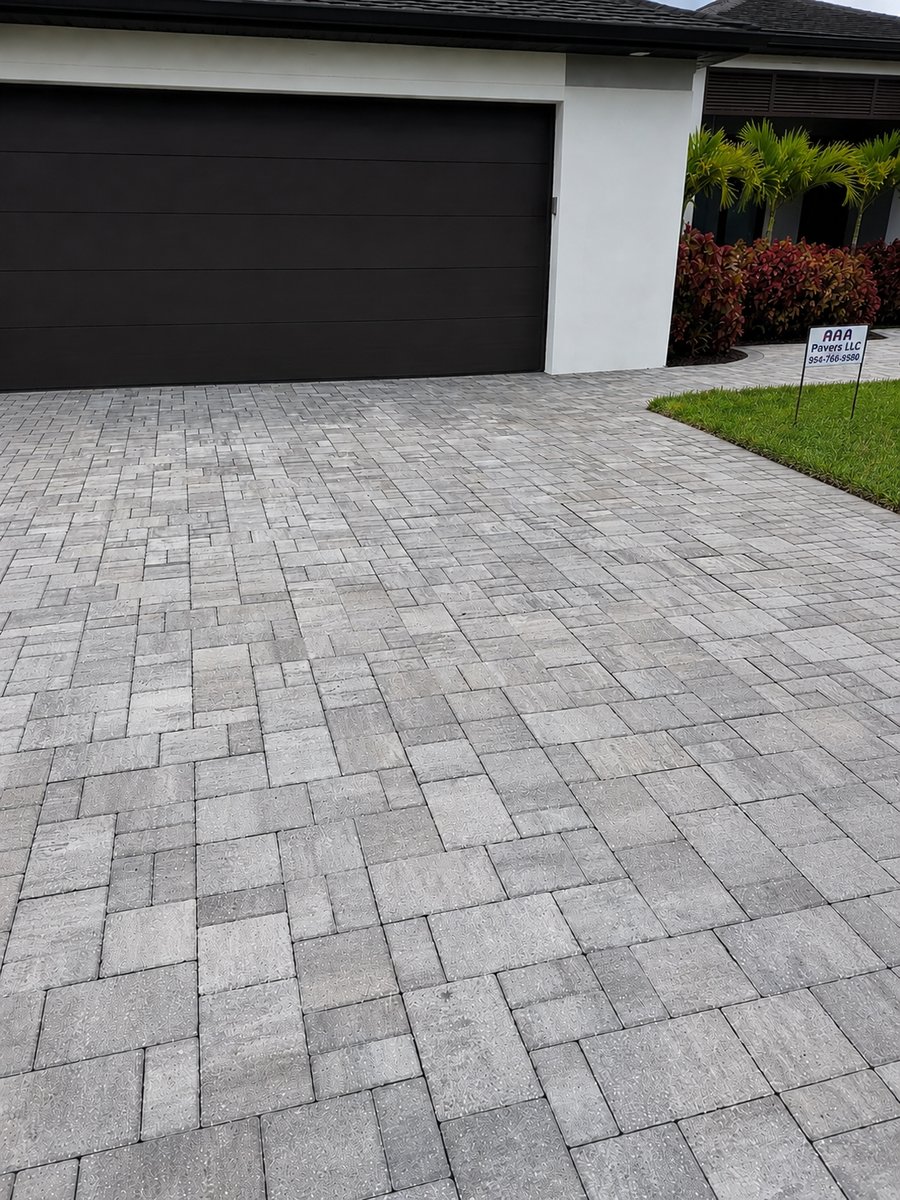 Close view of a grey large-format paver driveway laid in running bond up to a garage door