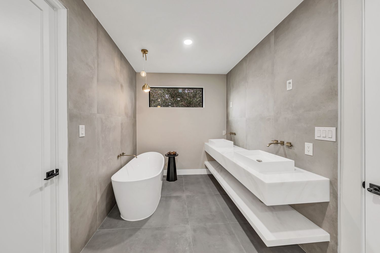 Completed bathroom with a freestanding tub and a pair of floating basins on a long vanity ledge