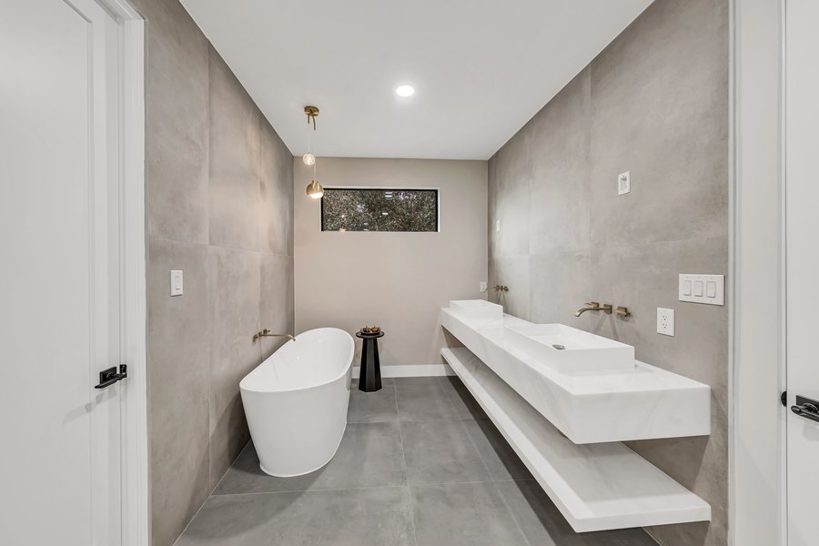Completed bathroom with a freestanding tub and a pair of floating basins on a long vanity ledge