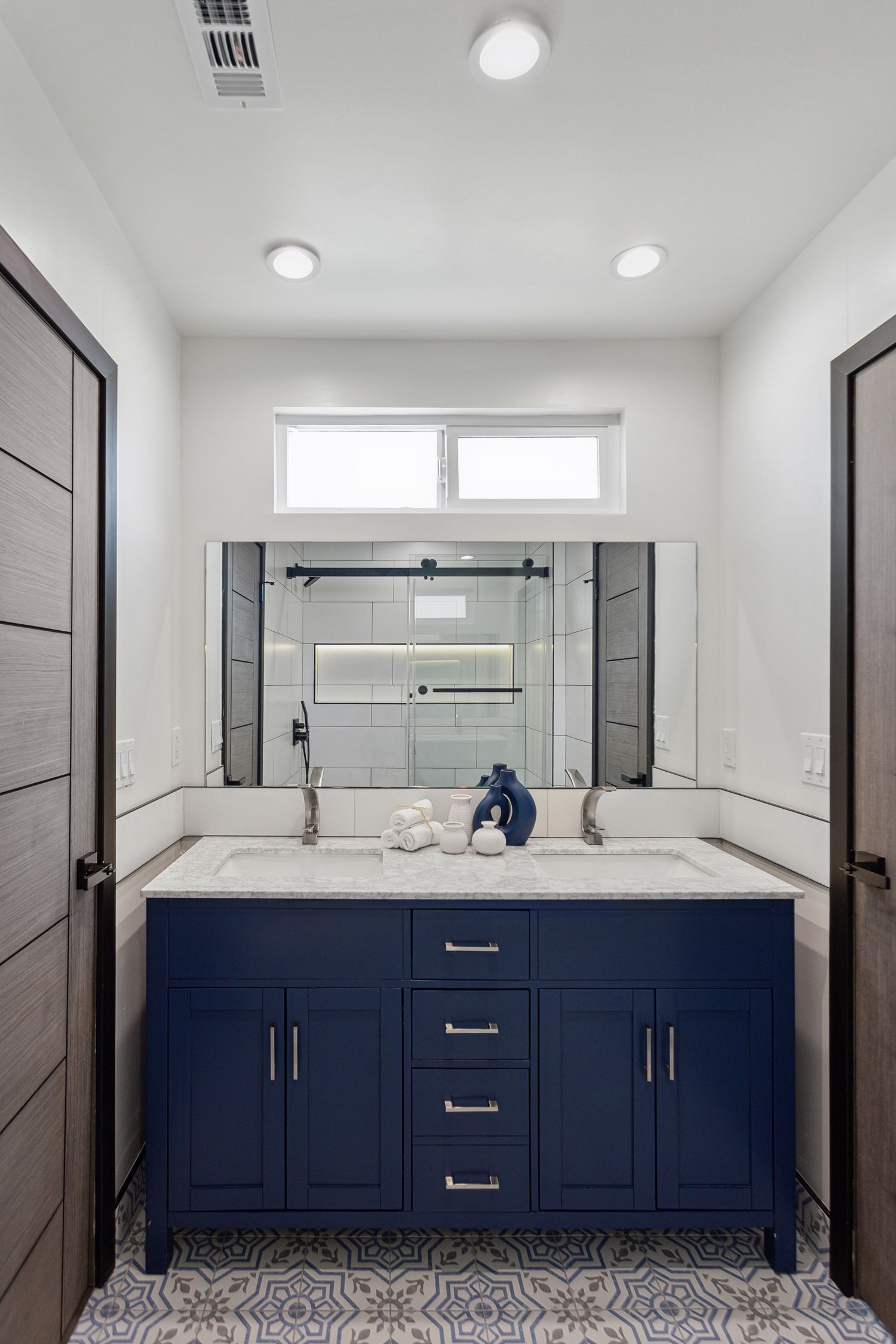 Navy blue vanity with a stone top and undermount basin beneath a wall mirror