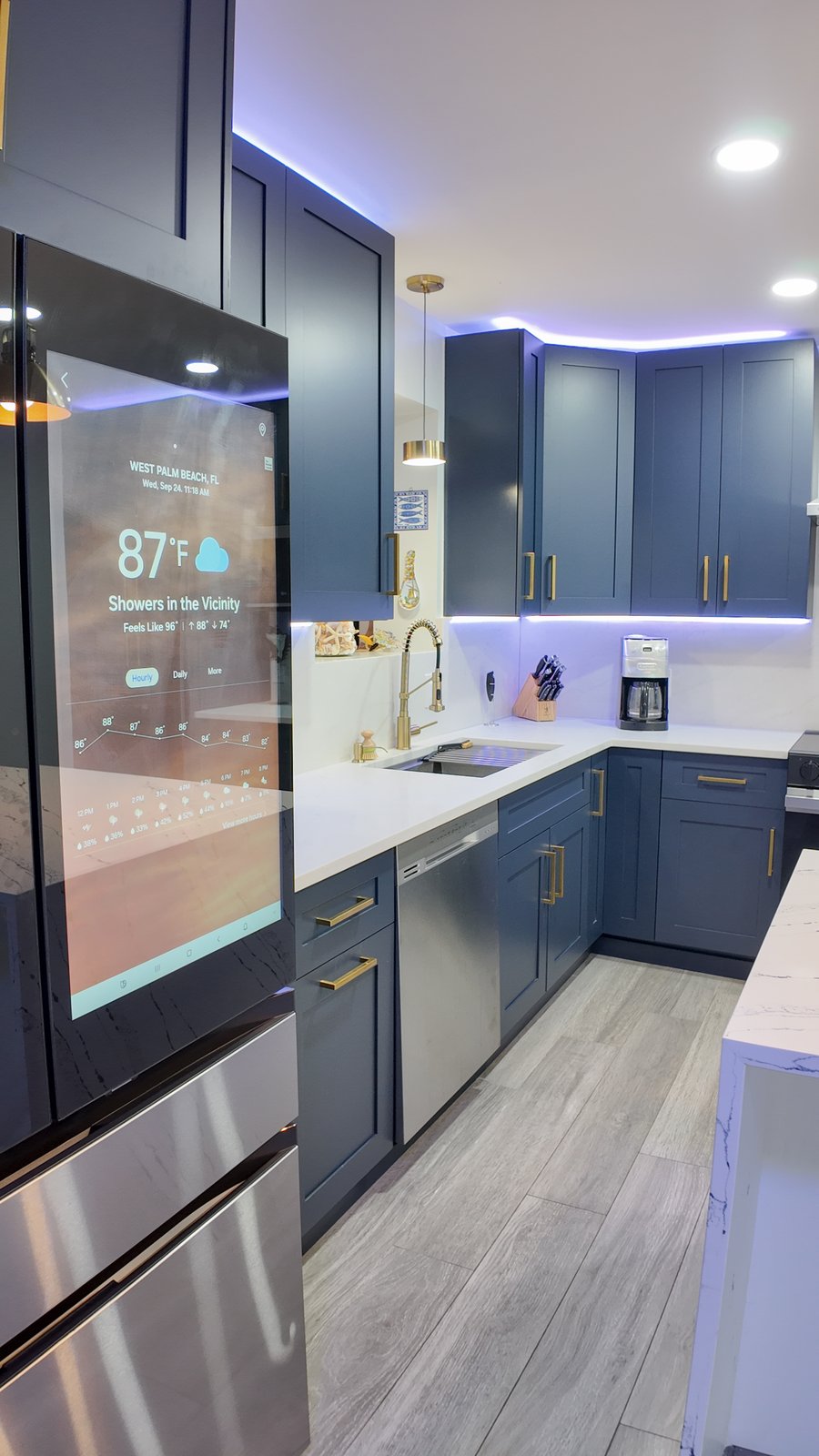 Navy kitchen cabinetry with a stone worktop and integrated appliances along the perimeter