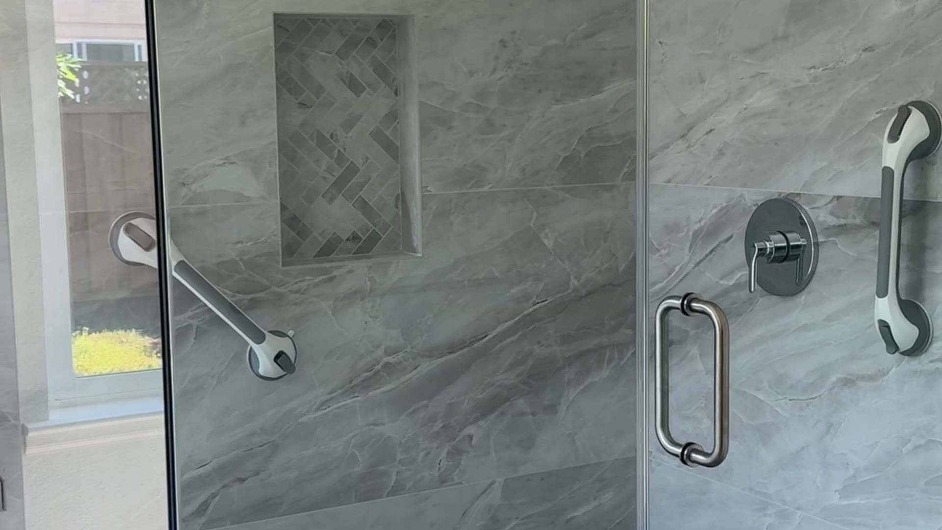 Walkthrough of a completed Elbaz Construction walk-in shower: marble-look porcelain, a tiled bench, grab bars and a linear drain