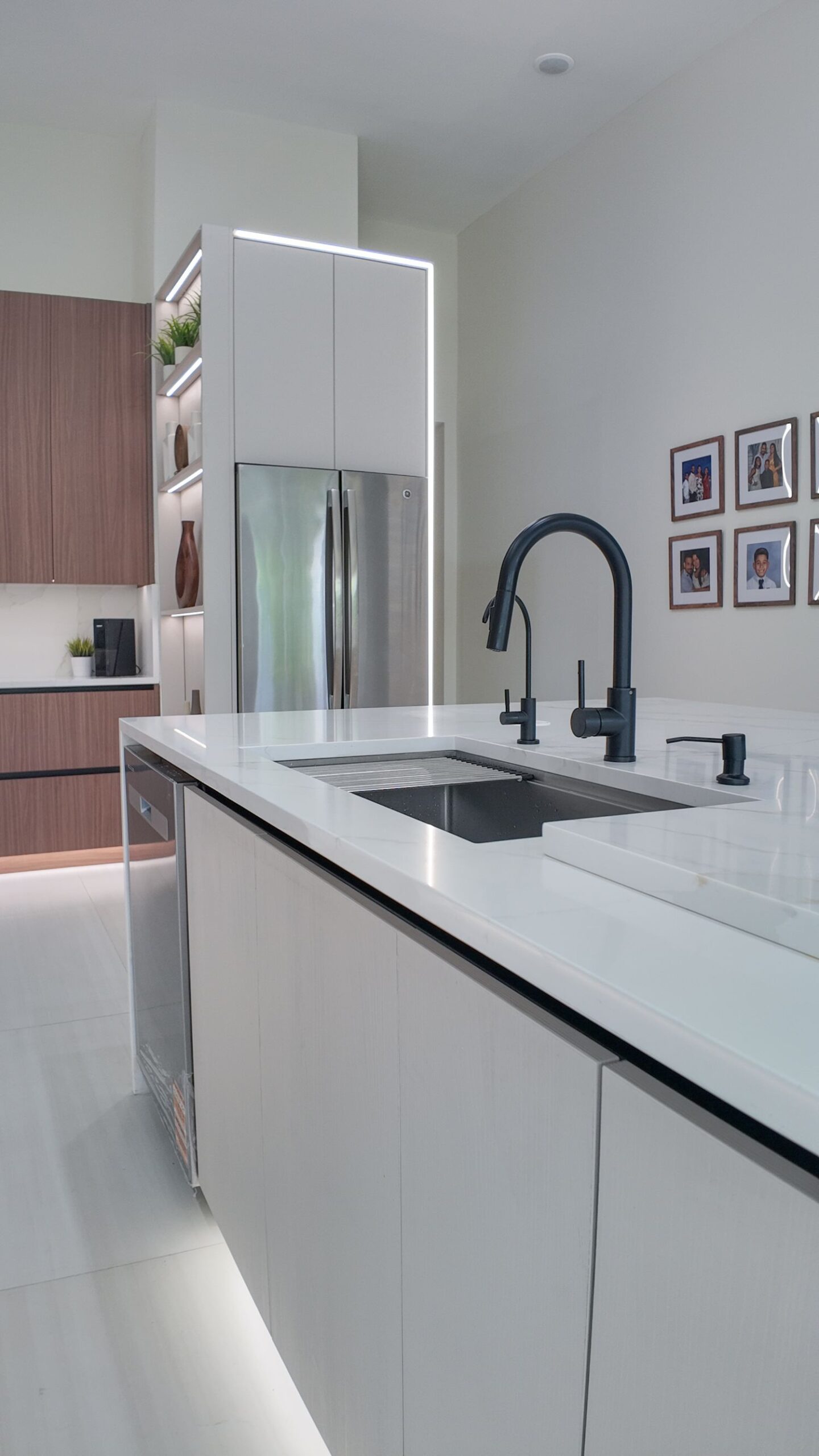 Undermount sink and black mixer set into a stone kitchen island top, with an integrated dishwasher in the run