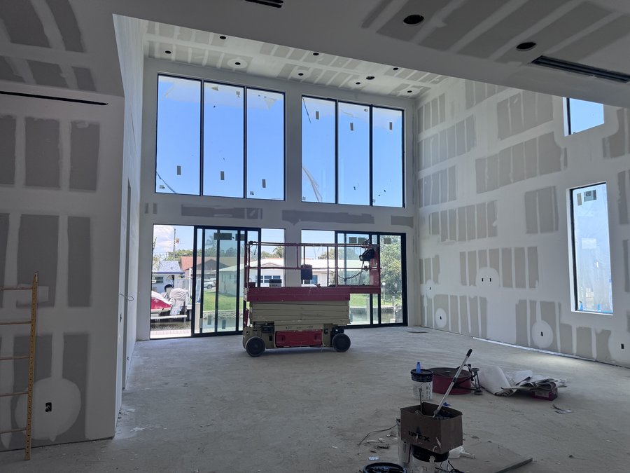 Double-height interior under construction with full-height glazing and drywall going up