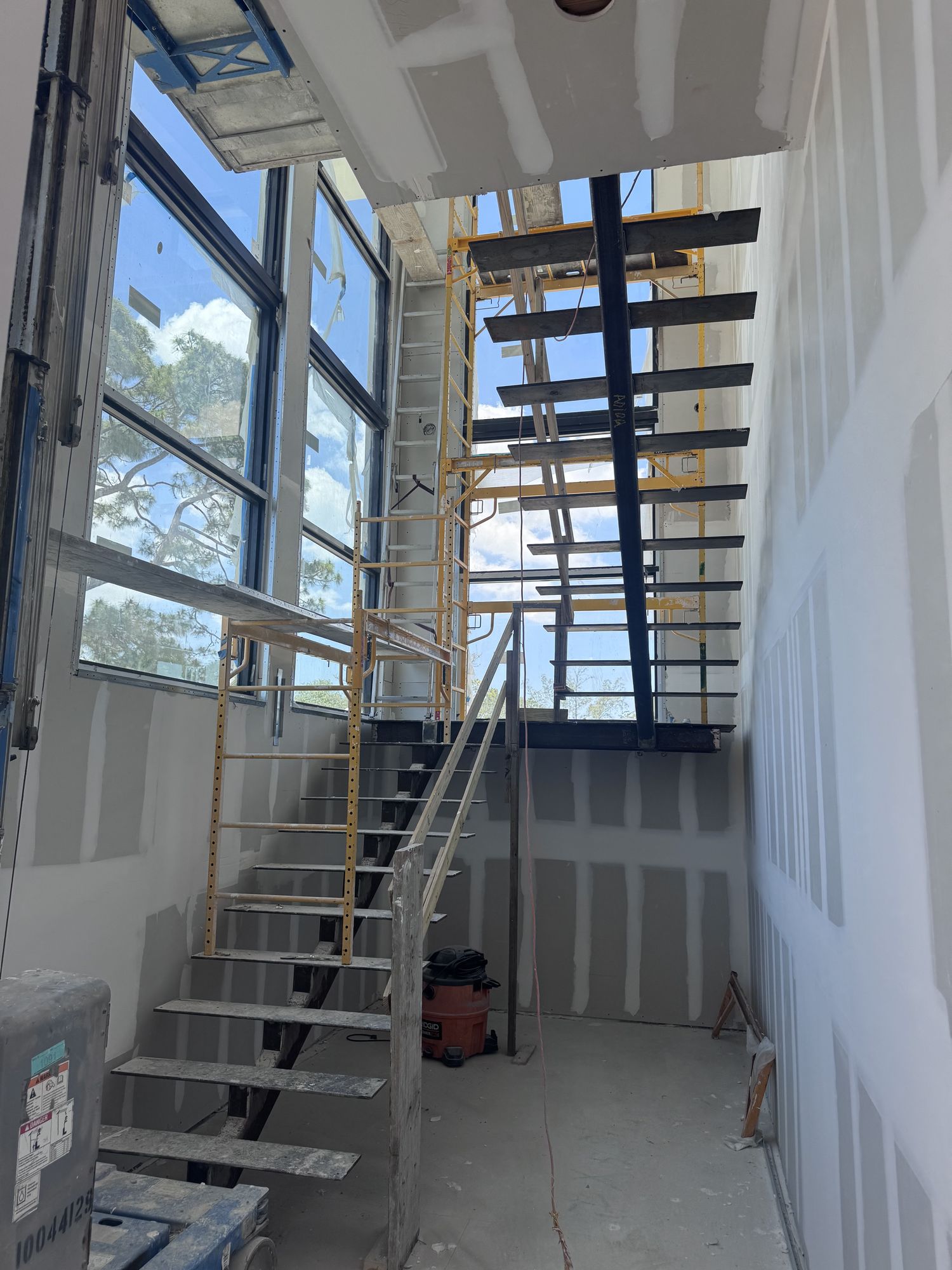 Steel stair structure installed inside a building under construction with scaffolding alongside