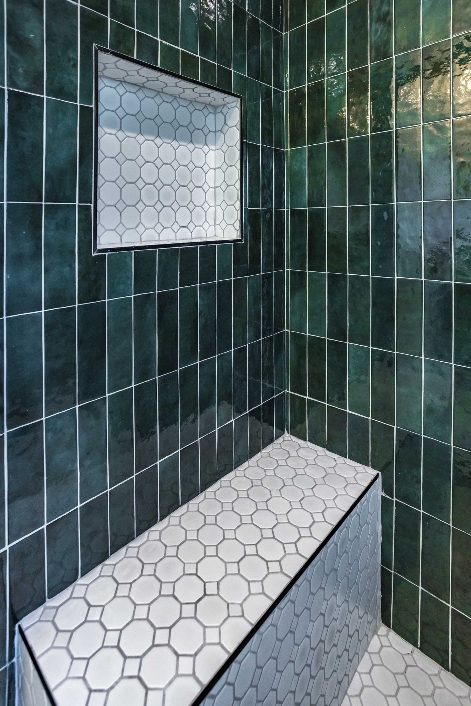 White hexagon mosaic shower bench against emerald green vertical stacked tile