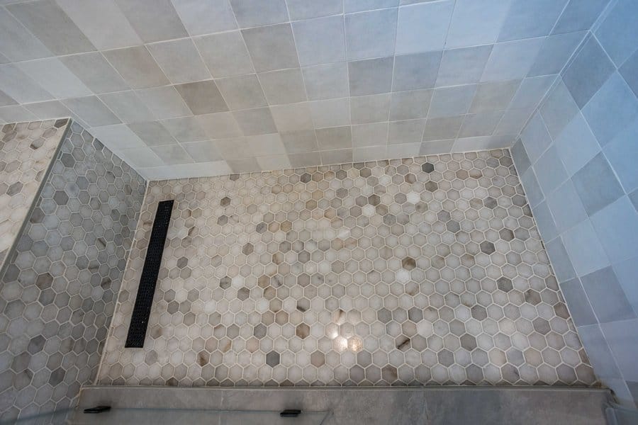 Hexagon mosaic shower floor with a linear drain along the glass line