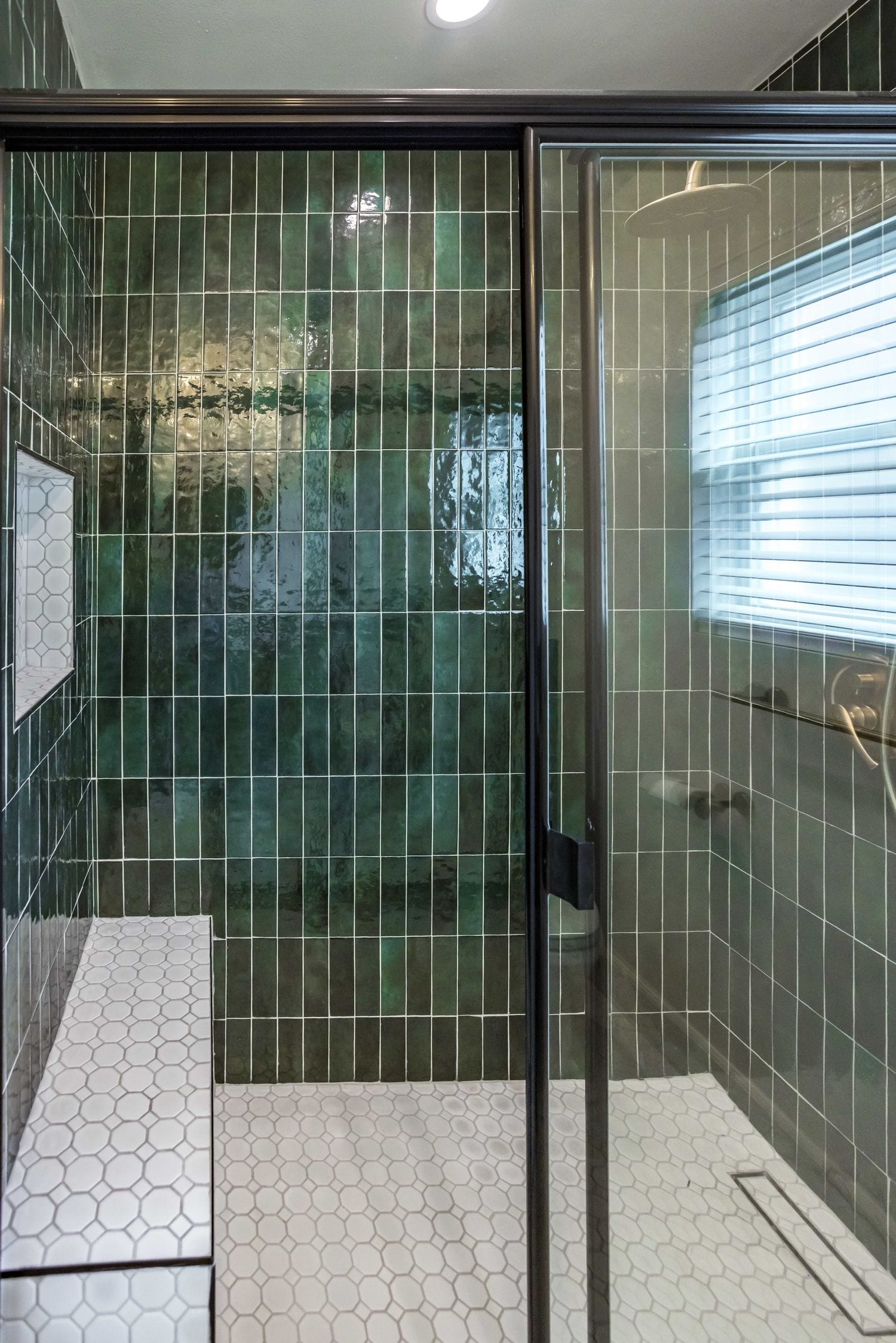 Linear drain set at the edge of a white hexagon mosaic shower floor