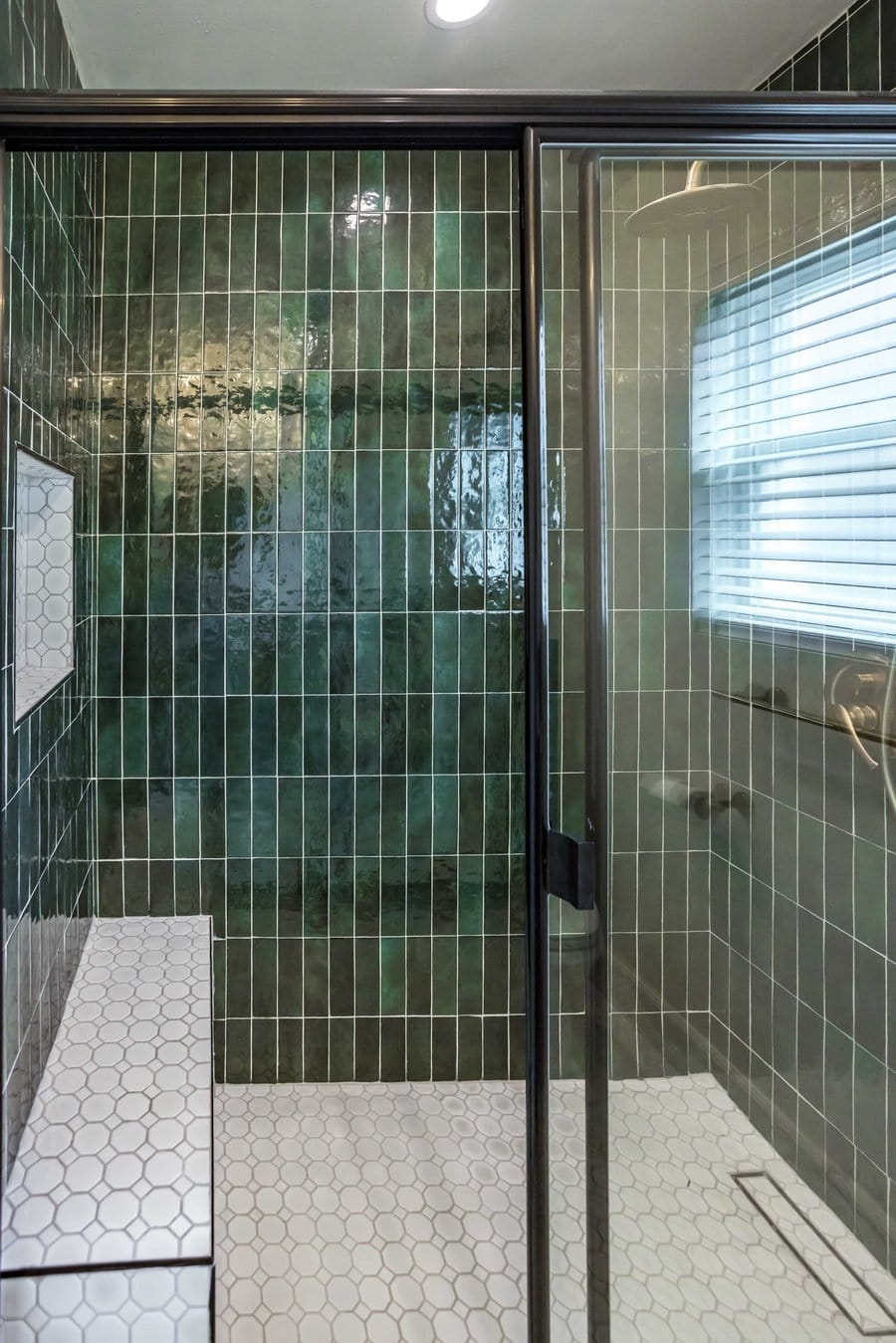 Linear drain set at the edge of a white hexagon mosaic shower floor