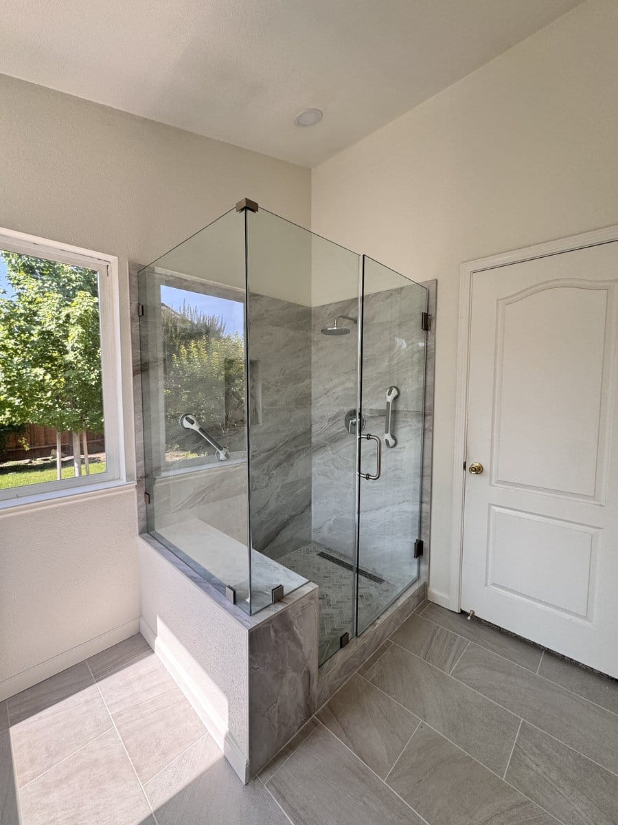 Tiled shower bench and low threshold seen from the bathroom floor through the open glass return