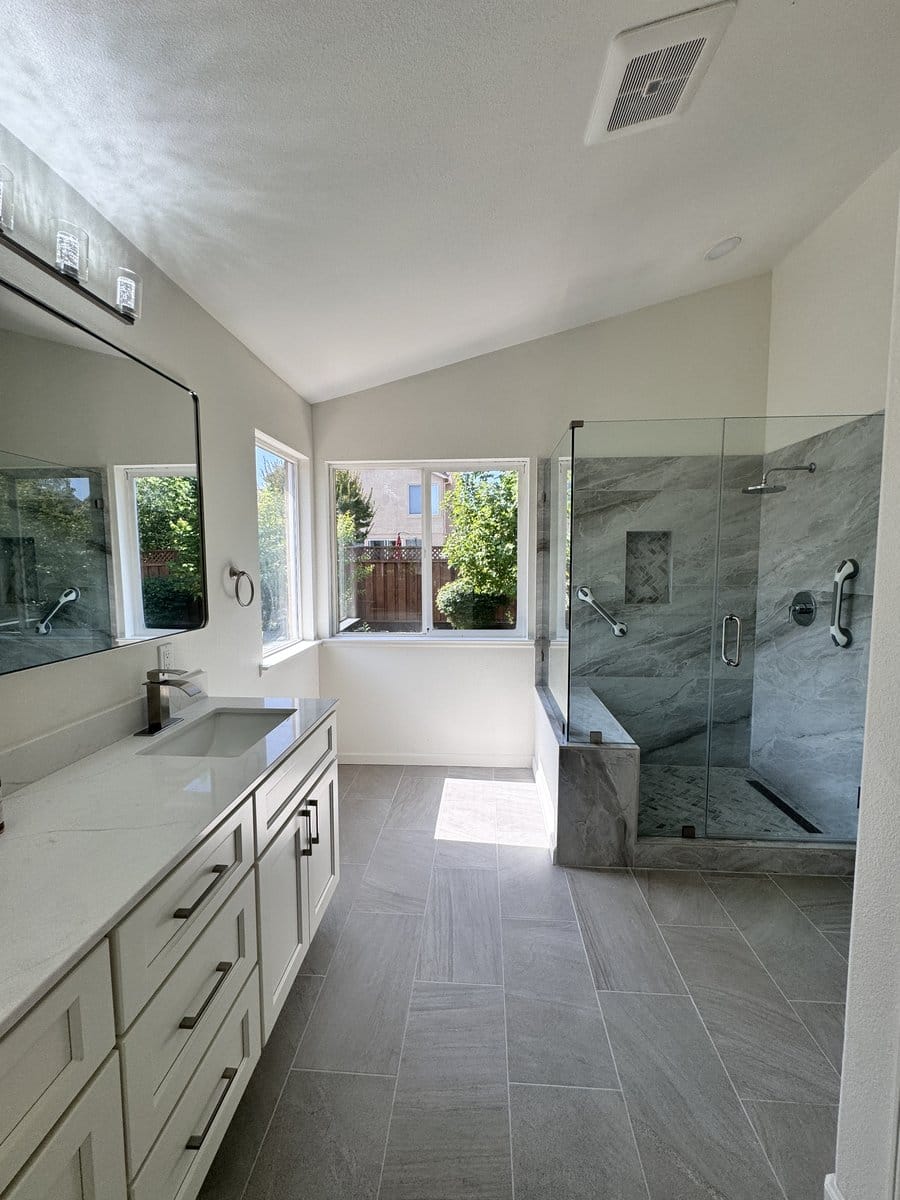 Primary bathroom with a vaulted ceiling, long vanity and glass-enclosed walk-in shower