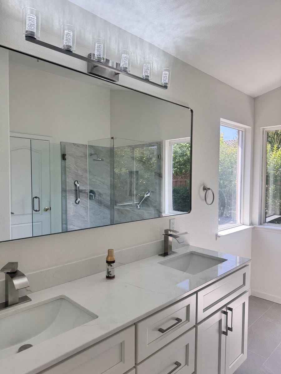 Double vanity below a long frameless mirror and a four-globe vanity light