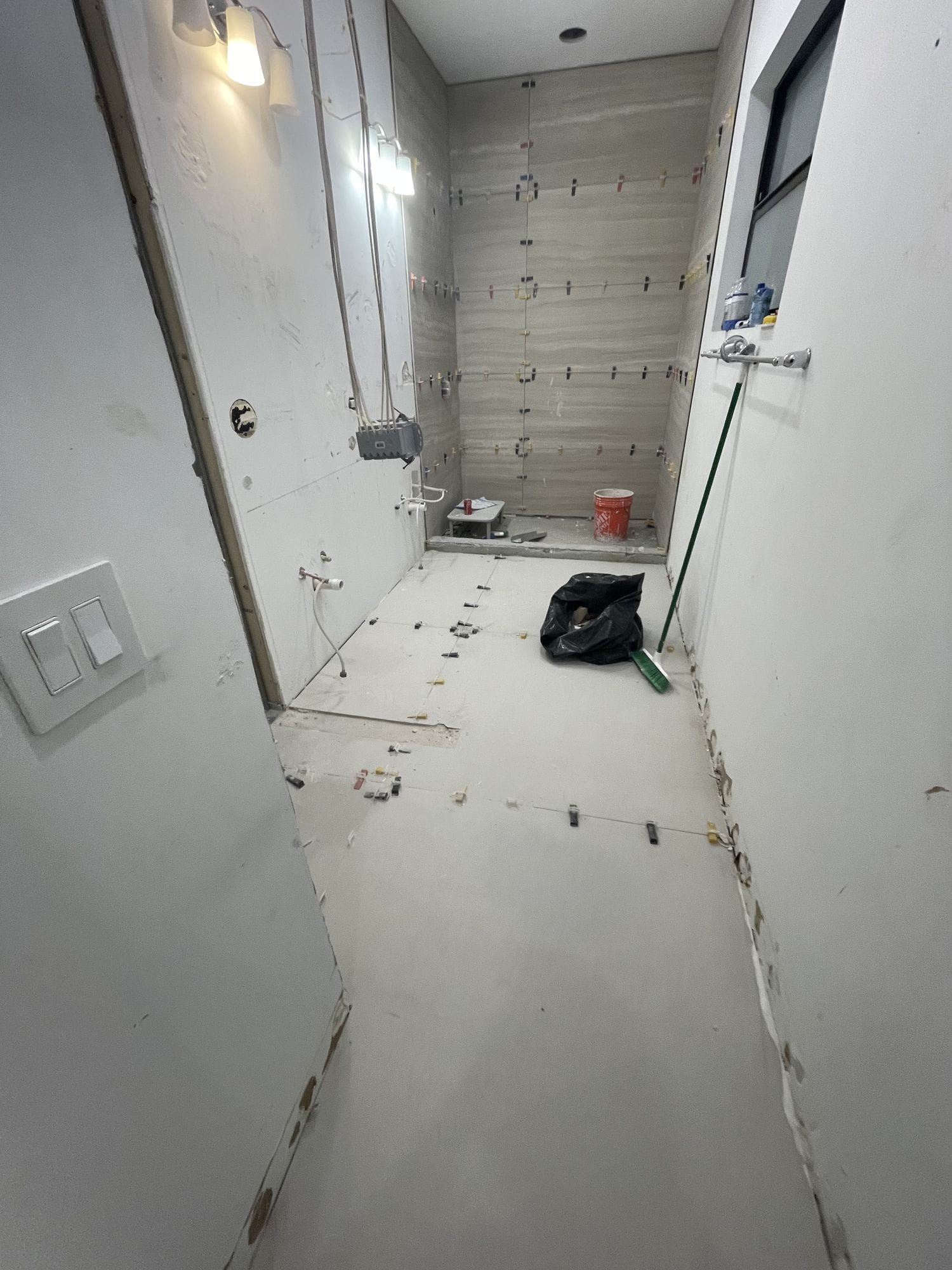 Shower walls part-tiled in vertical stacked plank tile with layout marks still visible on the floor