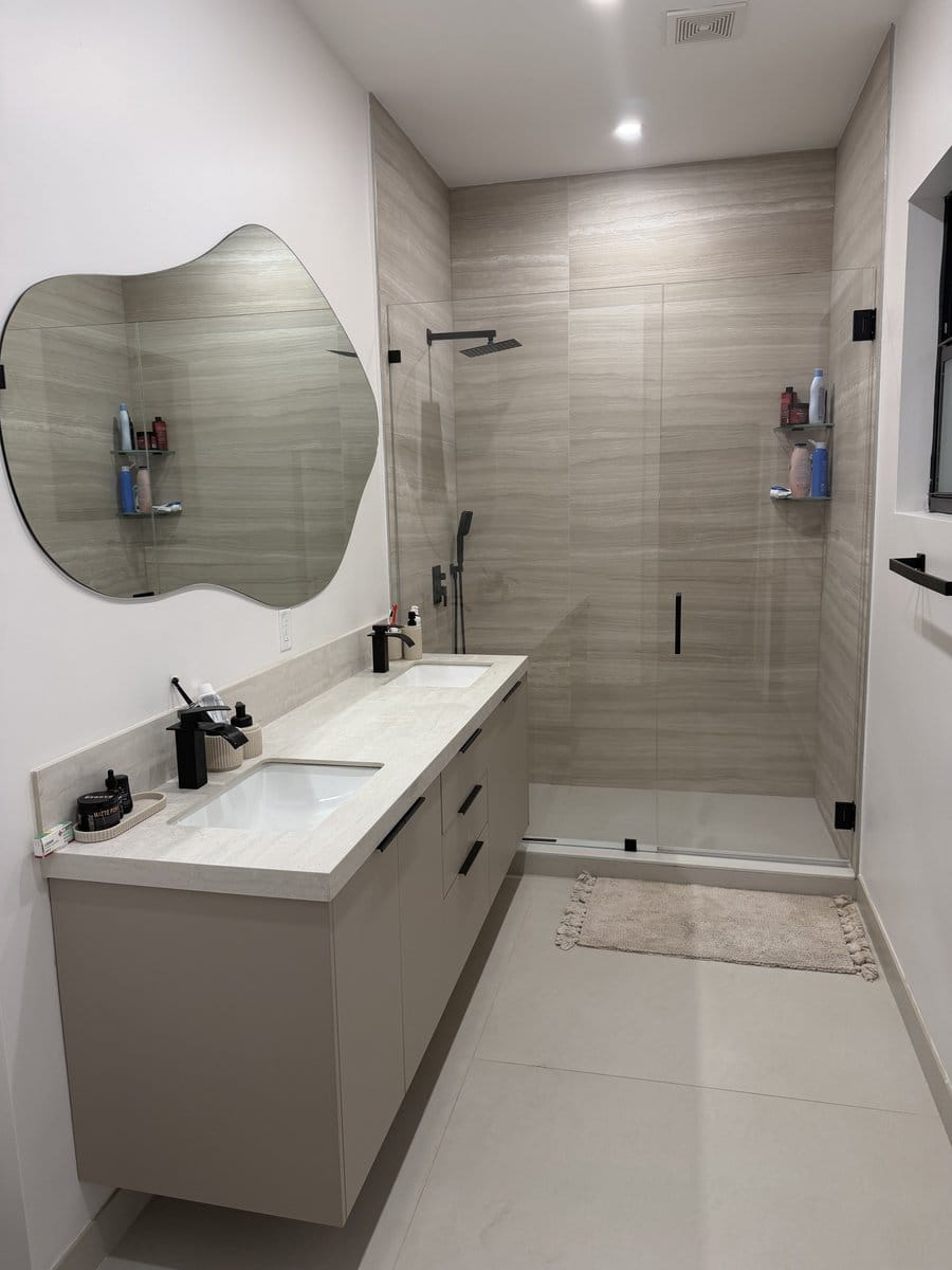 Curbless walk-in shower in stacked plank tile behind a frameless glass panel with black fittings
