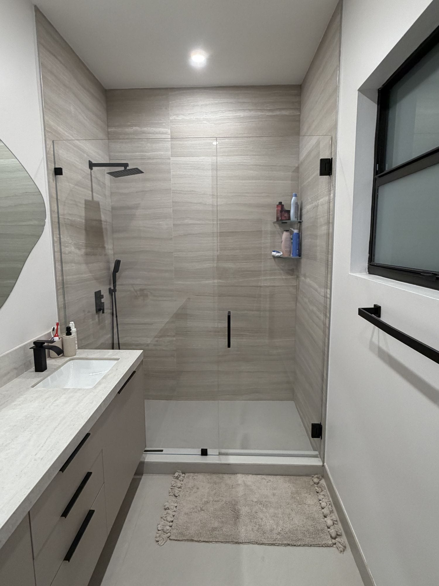 Level threshold between the bathroom floor and the shower floor with a black shower set beyond