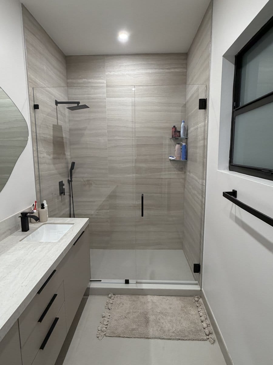 Level threshold between the bathroom floor and the shower floor with a black shower set beyond