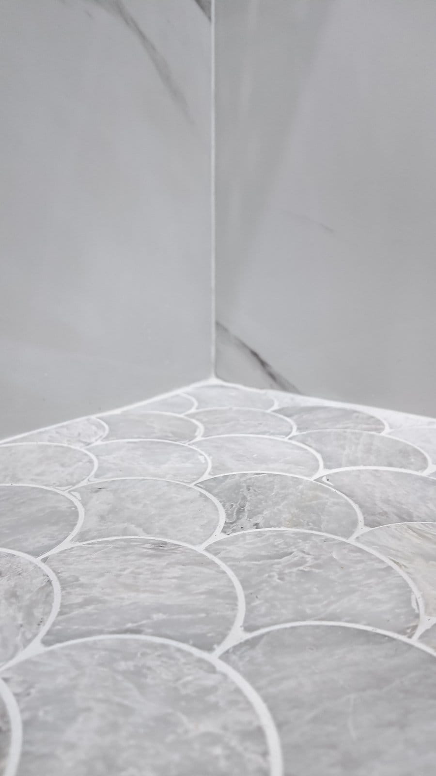 Scallop-pattern marble mosaic shower floor laid to fall