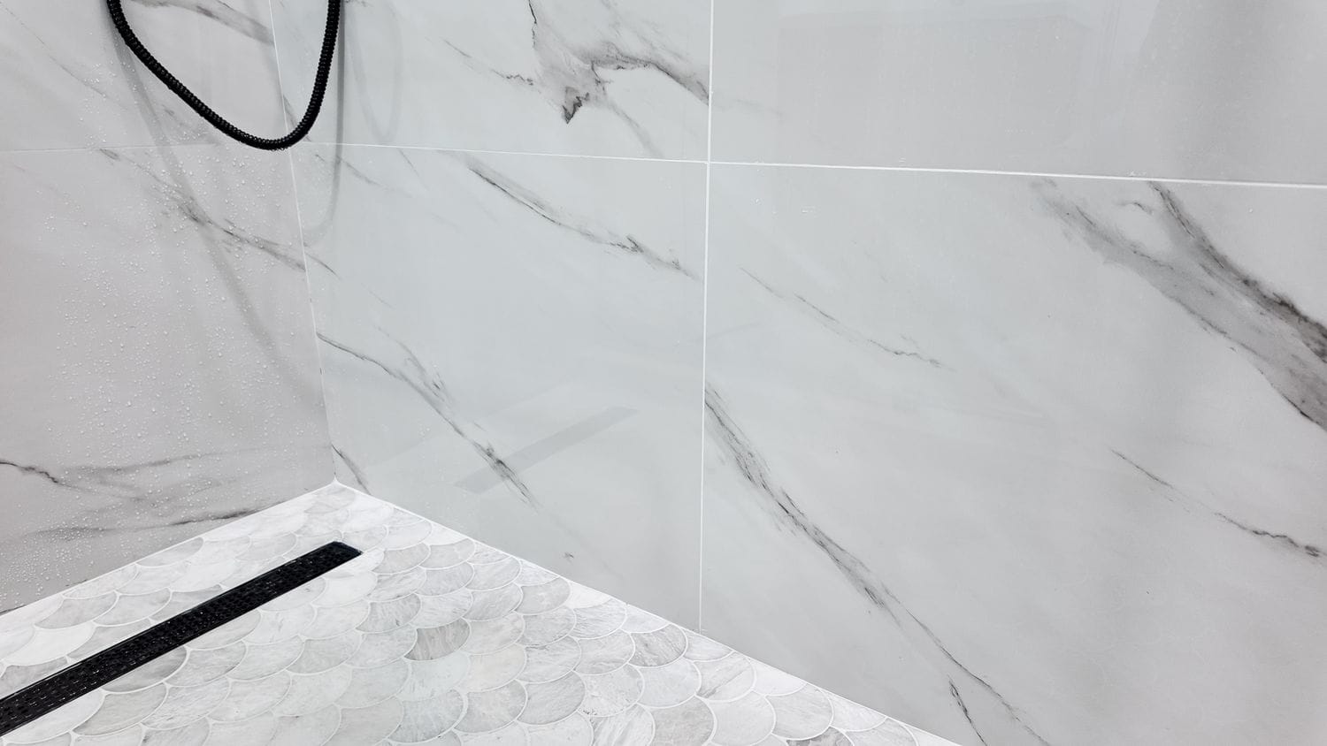 Low shower threshold with the linear drain running along the mosaic floor edge