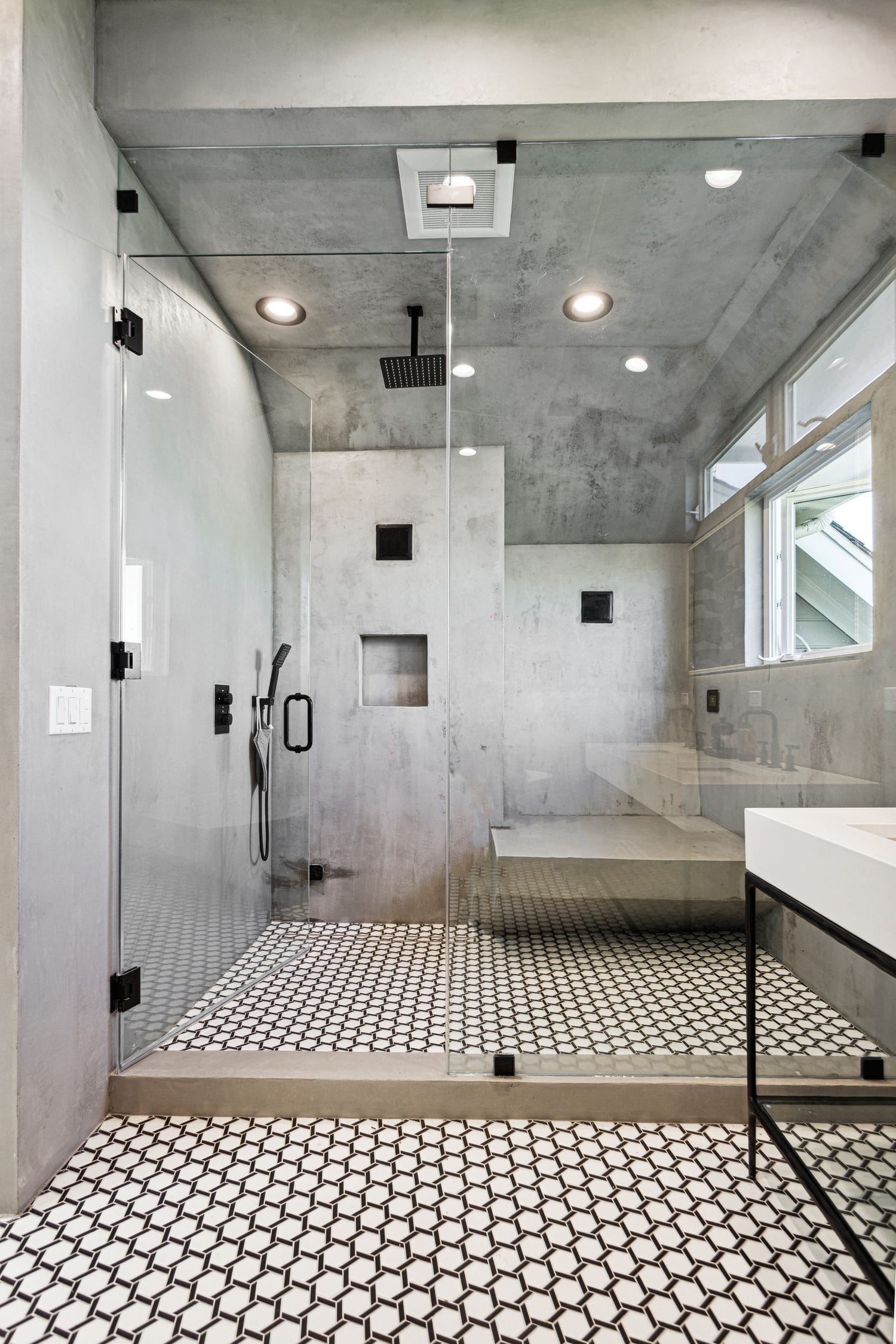 Curbless walk-in shower with a built-in bench, black rain head and a hexagon mosaic floor