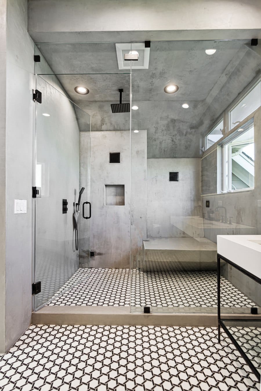 Curbless walk-in shower with a built-in bench, black rain head and a hexagon mosaic floor