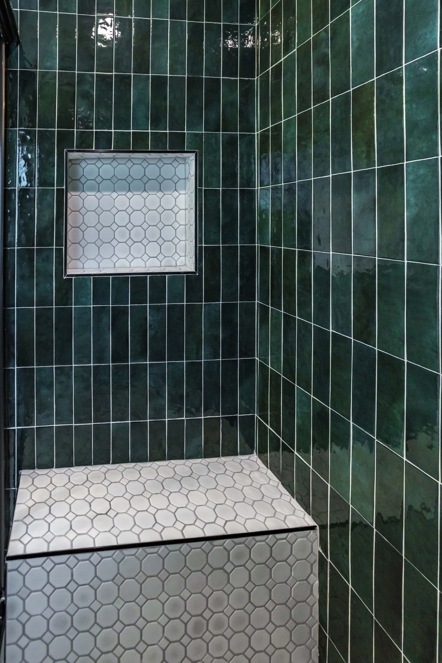 Emerald green tiled shower with a white hexagon mosaic bench and a recessed niche