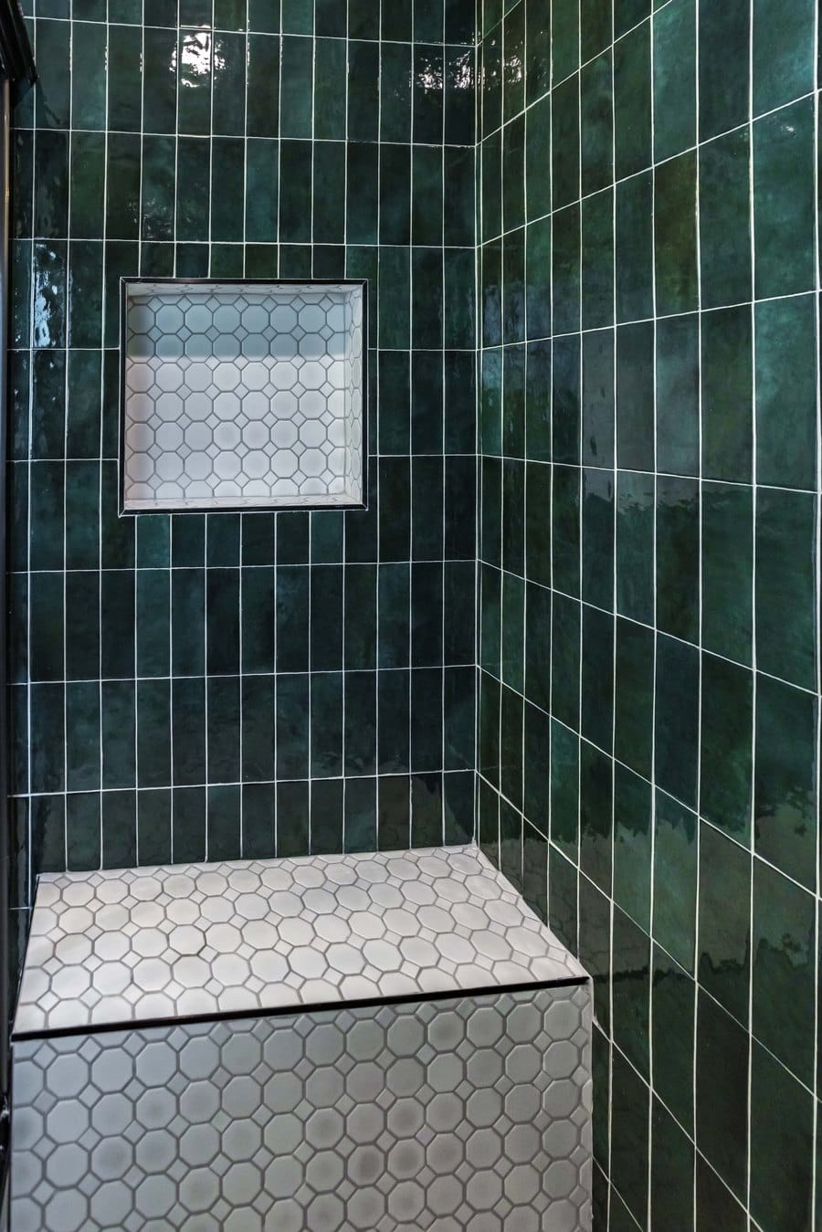 Emerald green tiled shower with a white hexagon mosaic bench and a recessed niche