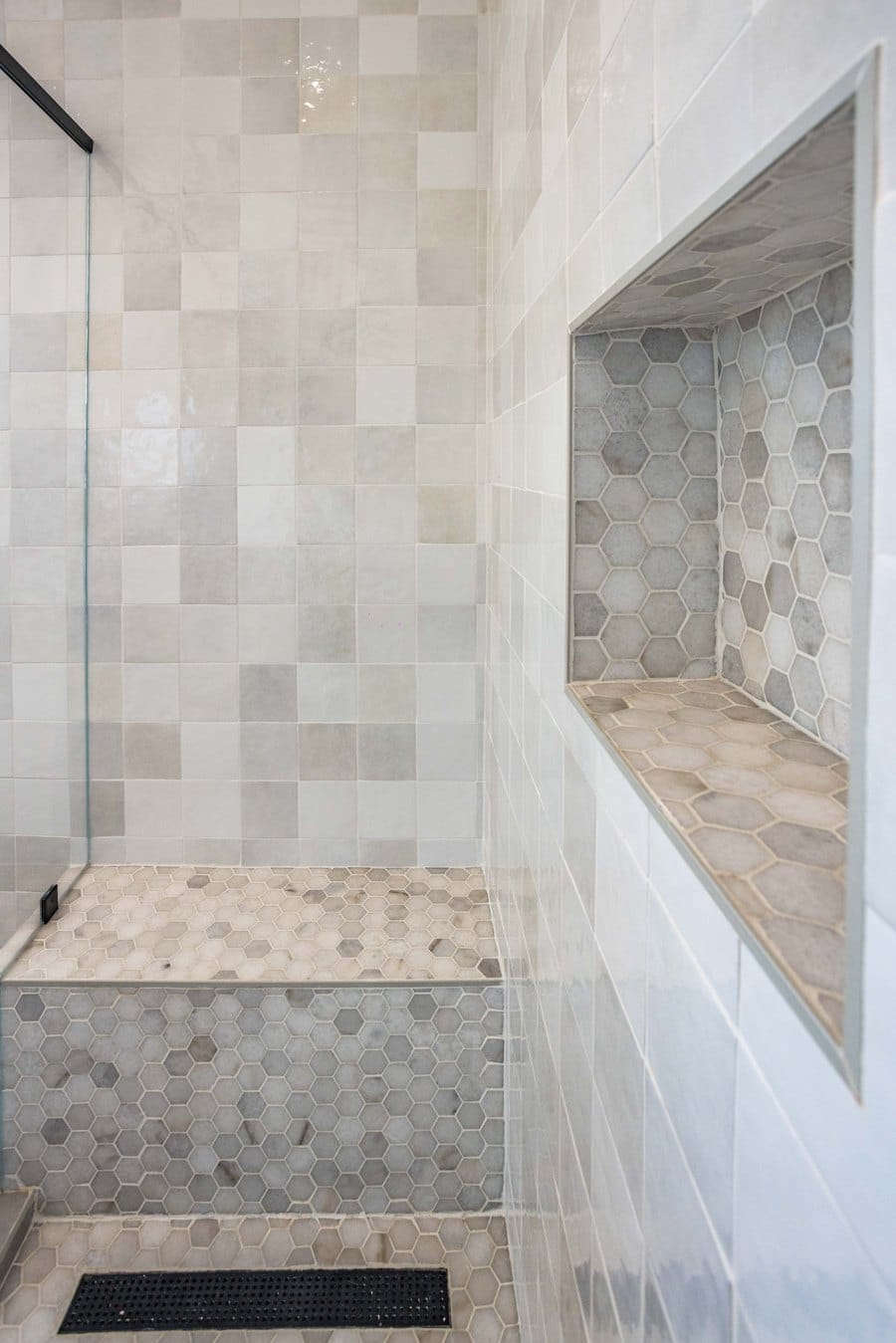 Walk-in shower with a tiled bench, hexagon mosaic niche and a linear drain along the glass line