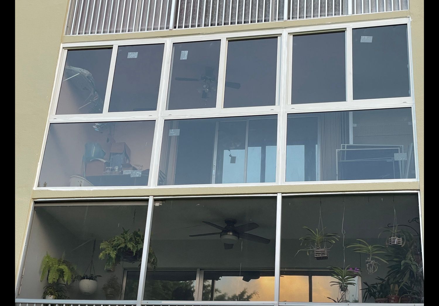 Multi-storey glazed elevation with dark framing over a screened terrace