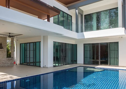 Full-height sliding glass walls opening a covered terrace onto a pool deck