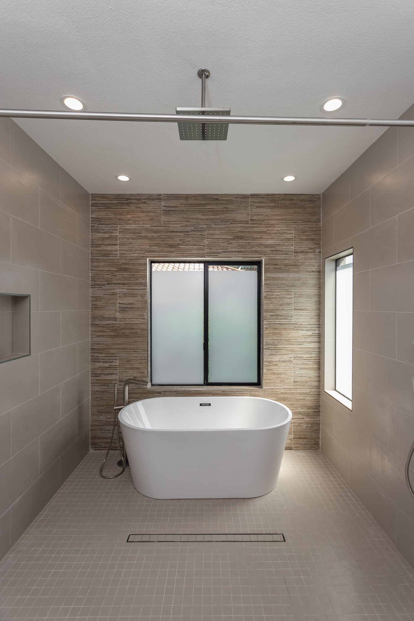 Bathroom with a freestanding bath and an adjoining level shower zone under a ceiling rain head