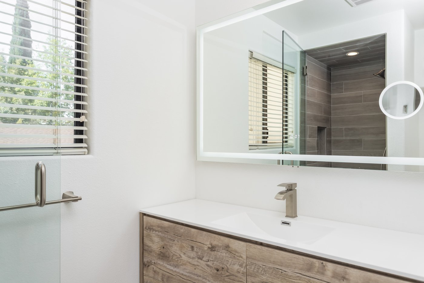 Wood-fronted floating vanity with an illuminated mirror and a wide basin