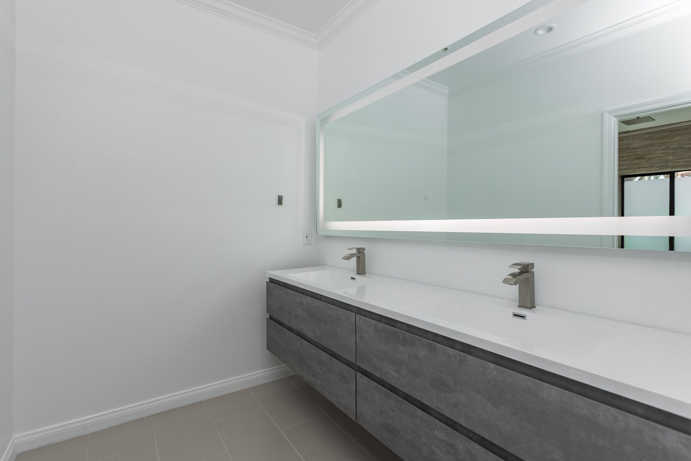 Wall-hung double vanity with open space beneath it and a full-width mirror above