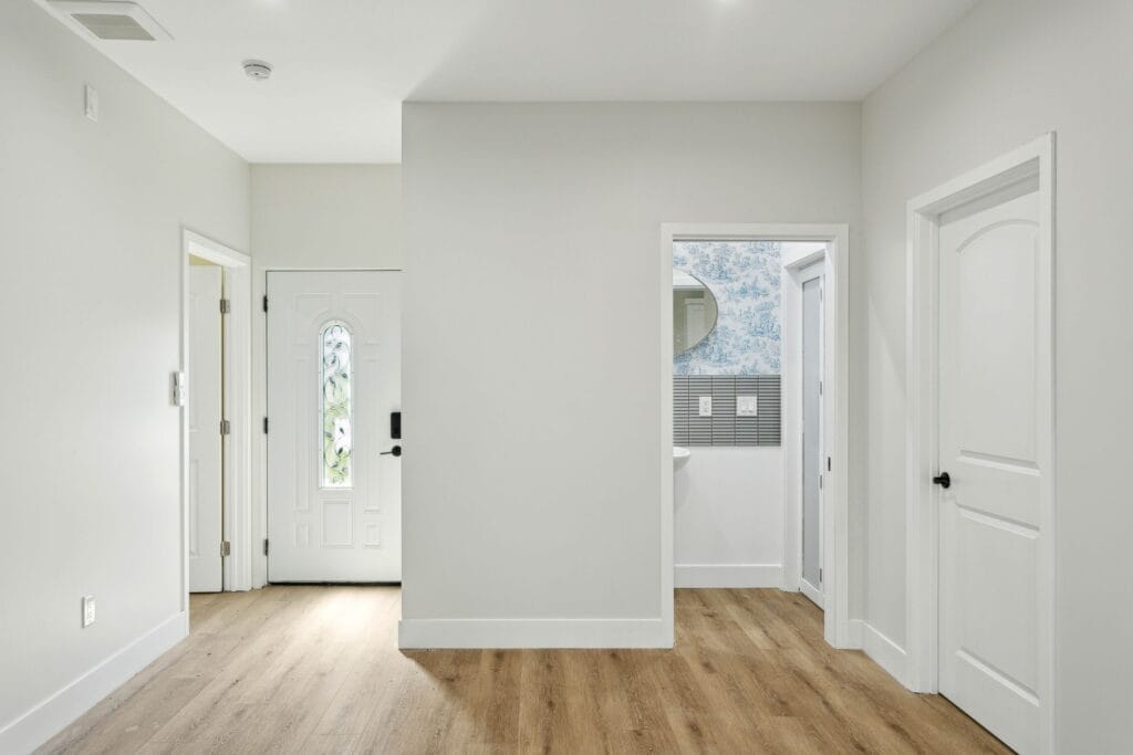 Interior entry with a glazed front door, white walls and wood-look plank flooring running through to the rooms beyond