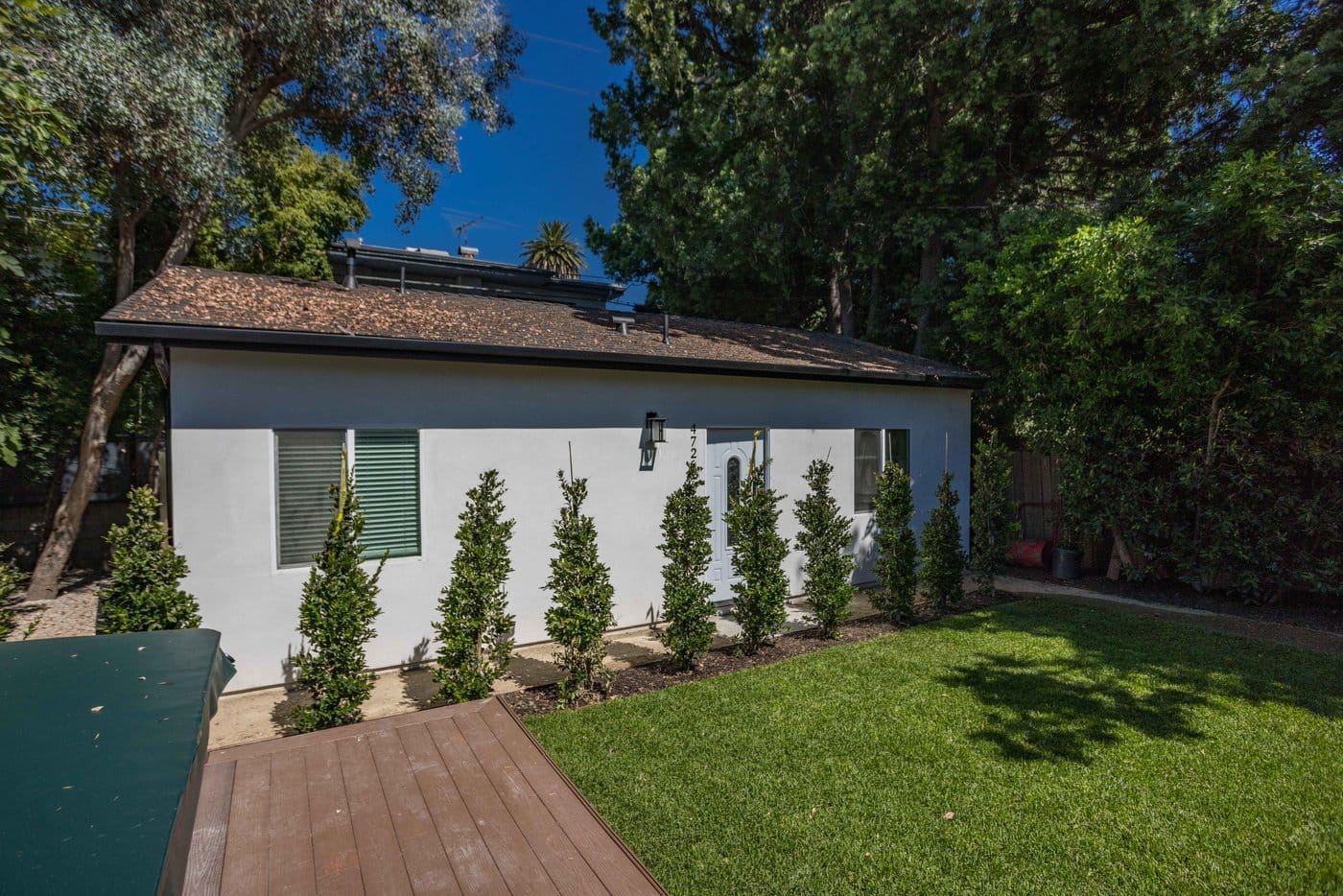 Narrow side elevation with a concrete path running between the unit and a clipped hedge