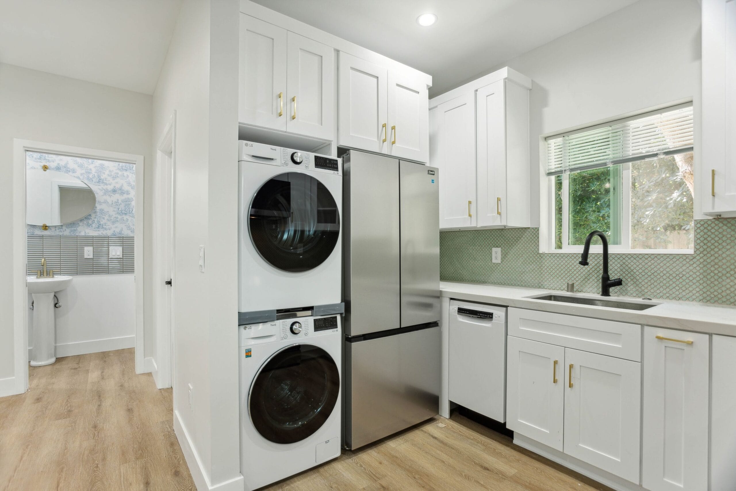 The kitchen looking back toward the entry, sink under the window and the laundry column on the left