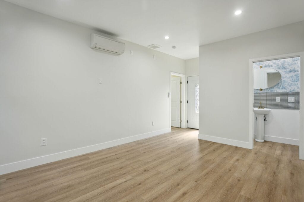 Living area with a wall-mounted mini-split head, recessed lighting and a doorway through to the bathroom
