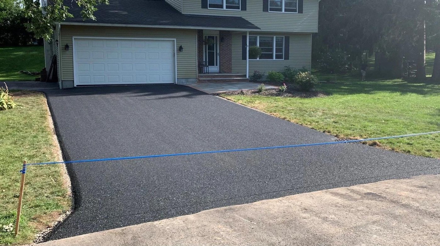 Dark coated driveway surface with a taped edge line during application