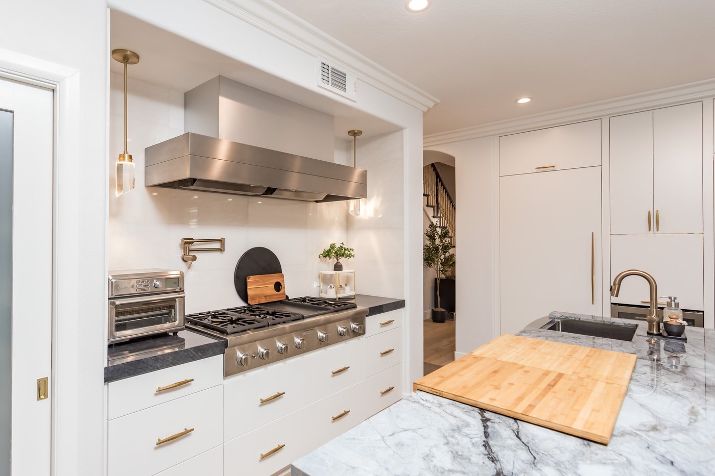 Tall cabinetry housing built-in ovens beside a wide drawer bank with brass hardware