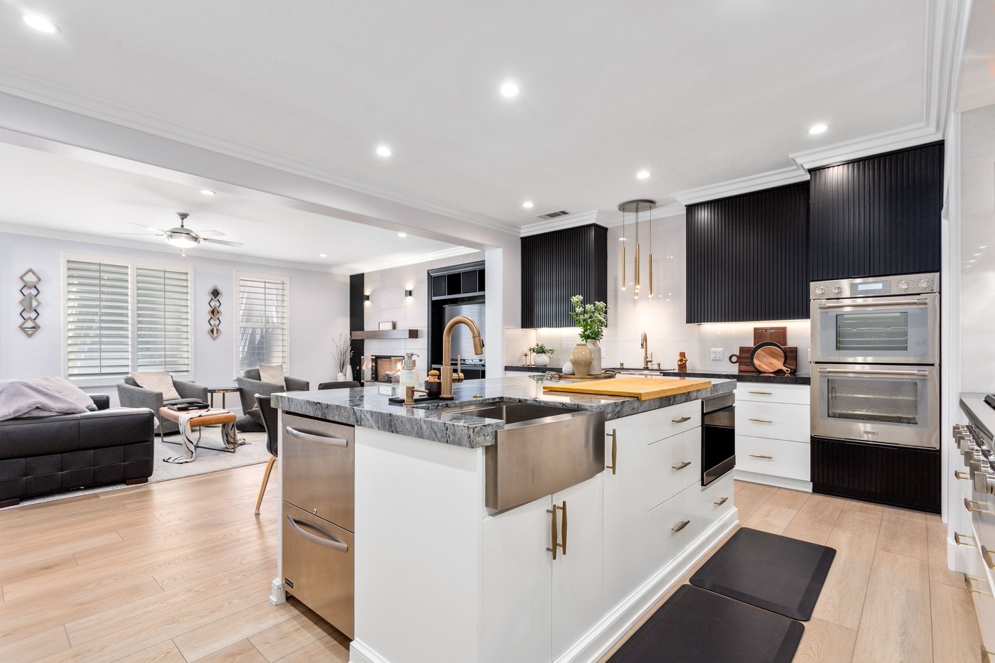 Kitchen run with white lower cabinetry, brass hardware and a marble worktop under wall units