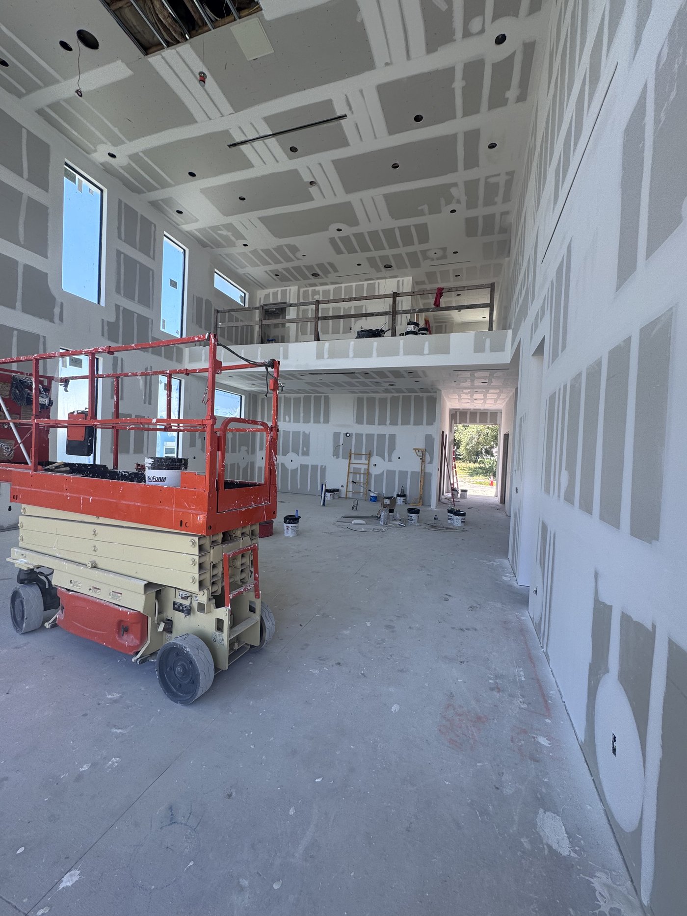 Interior at drywall stage with a scissor lift positioned for high-level work