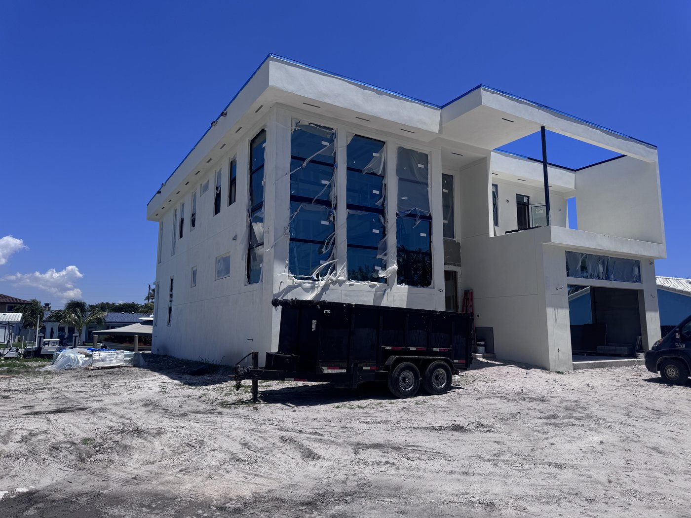 Side elevation of a two-storey new build with stacked window openings above a compacted sand working surface