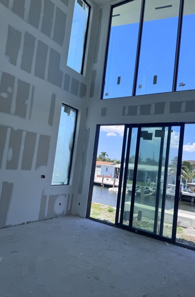 Multi-slide glass door seen from inside a South Florida house by Elbaz Construction, opening onto the canal