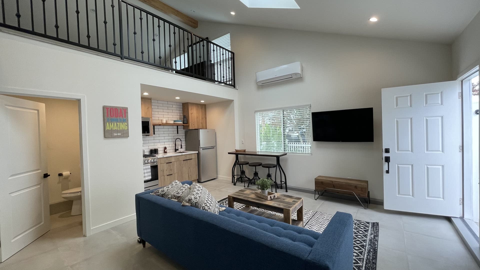 Interior of a detached ADU looking toward the entry door, with a vaulted ceiling, skylight and an open living area